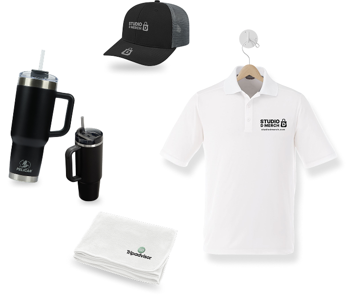 Merchandise set featuring custom merchandise: a black cap, white polo shirt, two black travel mugs, and two white towels. The cap and shirt display Studio D Merch logos; towels showcase a green Tripadvisor logo—perfect branded products for any promotion.