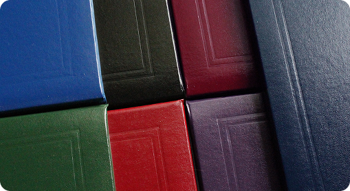 A close-up of six hardcover books arranged in a grid, each with a plain cover in various colors and embossed borders—perfect as custom merchandise or promotional products for your brand.