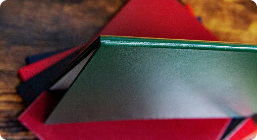 A close-up of several closed hardcover books with red and green covers, stacked on a wooden surface, ideal as branded products or custom merchandise.