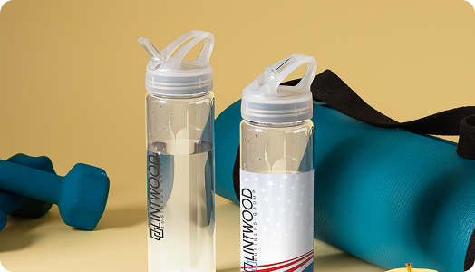 Two clear plastic water bottles, one with a label showcasing branded products, stand on a yellow surface next to a teal exercise mat and a blue dumbbell, set against a light yellow background.